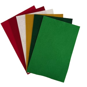 May include: A fan of colorful felt sheets in shades of red, white, gold, dark green, and bright green. The felt sheets are arranged to display the various colors. These sheets are likely used for crafting and DIY projects.