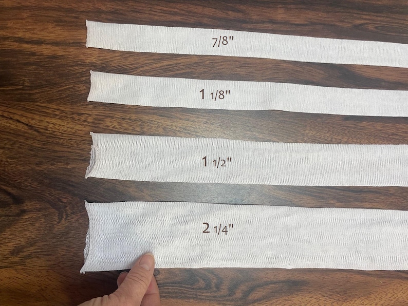 May include: Four white fabric strips with different lengths labeled in inches: 7/8", 1 1/8", 1 1/2", and 2 1/4".