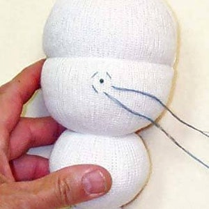 May include: A white sock doll with blue thread sewn for the mouth. The doll is made from two white socks, one for the head and one for the body.