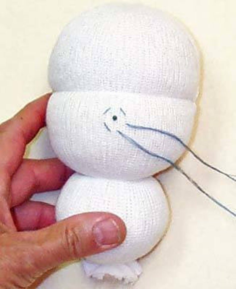 May include: A white sock doll with blue thread sewn for the mouth. The doll is made from two white socks, one for the head and one for the body.