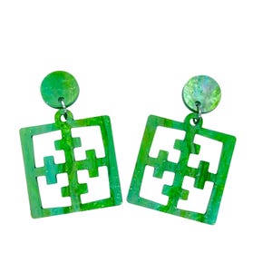 May include: A pair of green and white marbled earrings. Each earring features a circular stud and a square pendant with a cut-out geometric design. The earrings are a vibrant accessory.