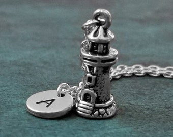 May include: A silver necklace featuring a lighthouse charm and a silver disc charm with the letter A engraved on it.