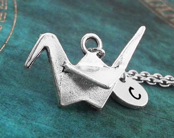 May include: Silver origami crane pendant necklace with a silver initial charm. The initial charm has the letter "C" on it.