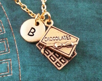 May include: Gold necklace with a charm that says "Chocolates" and a round charm with the letter "B".