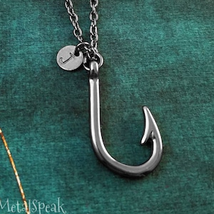 May include: A silver necklace with a fishing hook charm and a small silver disc with the letter 'J' on it.