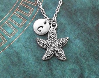 May include: A silver necklace with a starfish charm and a silver disc charm with the letter "C" on it.