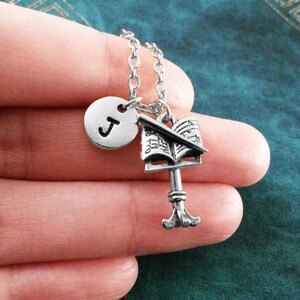 May include: Silver necklace with a music note charm, a treble clef charm, and a letter J charm.