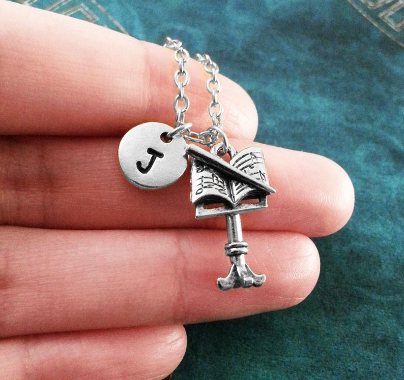 May include: Silver necklace with a music note charm, a treble clef charm, and a letter J charm.