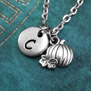 May include: A silver necklace with a silver charm that says "C" and a silver pumpkin charm.