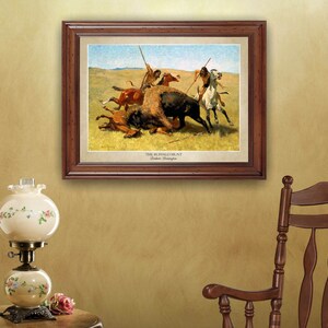 May include: A framed print of a painting depicting a buffalo hunt. The painting shows Native Americans on horseback, with spears, chasing a buffalo. The painting is titled "The Buffalo Hunt" by Frederic Remington.