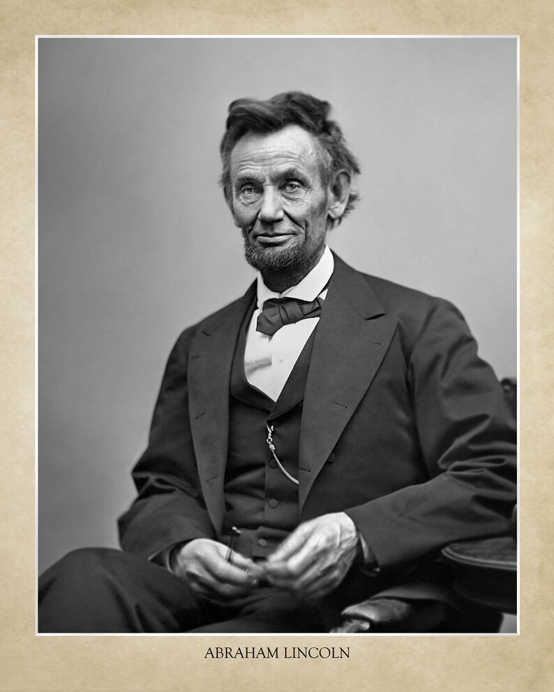 Puede incluir: Fotograf&iacute;a en blanco y negro de Abraham Lincoln, el 16&ordm; presidente de los Estados Unidos. Lleva un traje oscuro, una camisa blanca y una corbata de lazo oscura. Est&aacute; sentado y mirando directamente a la c&aacute;mara.