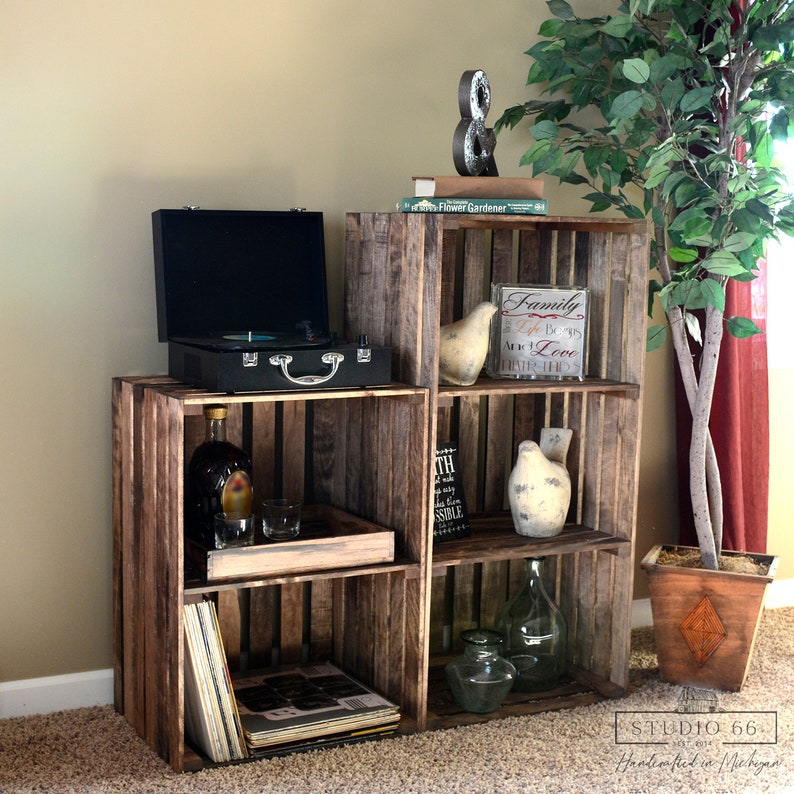 May include: A rustic wooden crate shelf unit with four shelves. The shelves are filled with various items, including a record player, a bottle of liquor, glasses, records, a book, a glass jar, and decorative bird figurines. The shelf unit is made of reclaimed wood and has a natural, distressed finish.