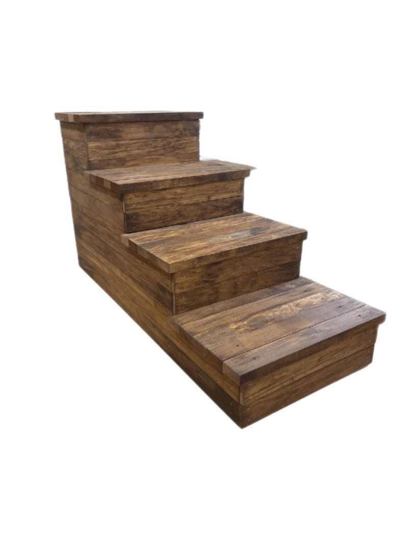 May include: A rustic wooden pet step with four steps. The steps are made of stained wood with visible grain, creating a natural, weathered appearance. The steps are designed to help pets reach higher surfaces.