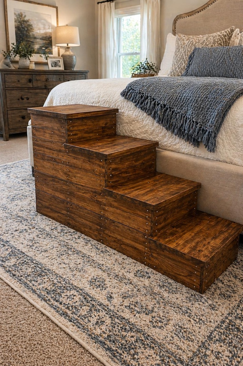 May include: A wooden pet step stool with four steps. The steps are stained a warm brown and are constructed with visible nail heads. The step stool is placed on a patterned rug in a bedroom setting.