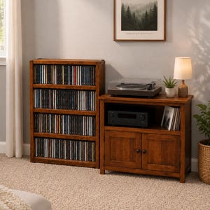 Peut inclure: Une tour multimédia en bois à quatre étagères remplie de disques compacts, placée à côté d'un meuble console multimédia en bois assorti. La console dispose d'une étagère supérieure ouverte avec une platine et un récepteur, et deux portes.