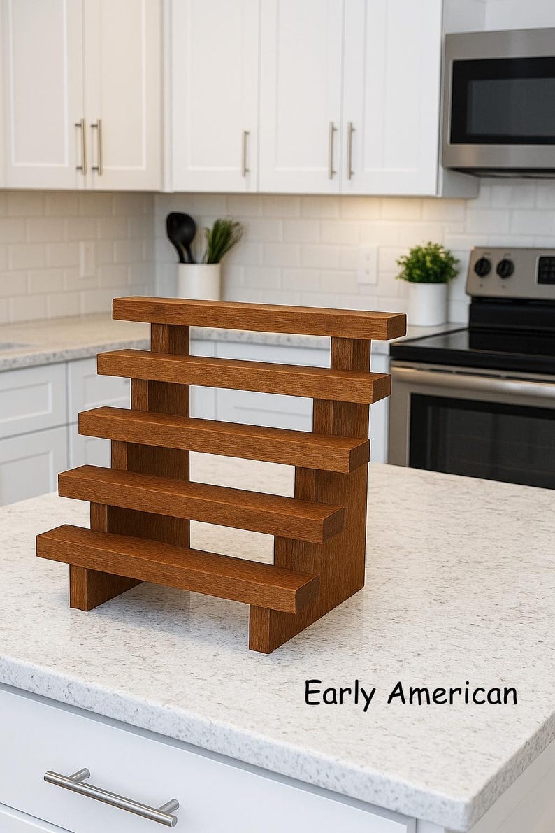 May include: A wooden, tiered spice rack with five shelves. The rack is made of a warm, medium-toned wood and is labeled "Early American". The shelves are supported by vertical beams, creating a stepped design. It is displayed on a white countertop.