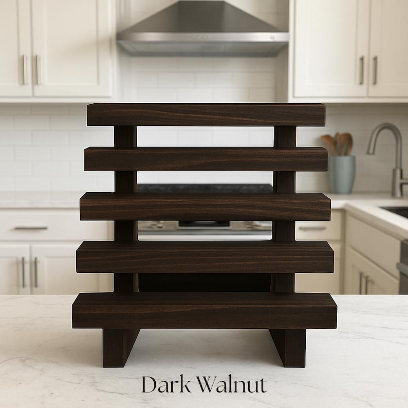 May include: A dark walnut-stained wooden display stand with five horizontal shelves. The stand is rectangular with a sturdy base and is designed to hold various items. The text "Dark Walnut" is at the bottom.