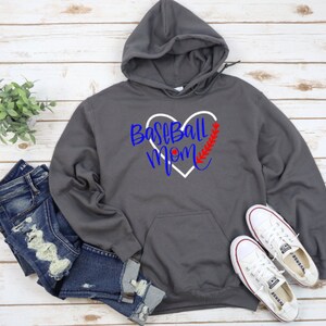 May include: Grey hooded sweatshirt with a white heart design that says "Baseball Mom" in blue lettering. The heart has a red baseball stitch design.
