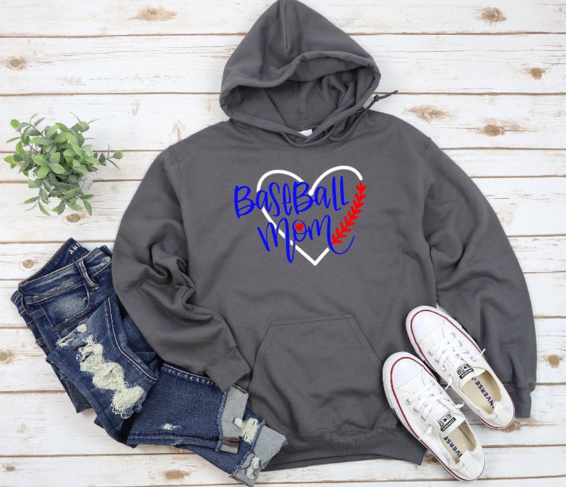 May include: Grey hooded sweatshirt with a white heart design that says "Baseball Mom" in blue lettering. The heart has a red baseball stitch design.