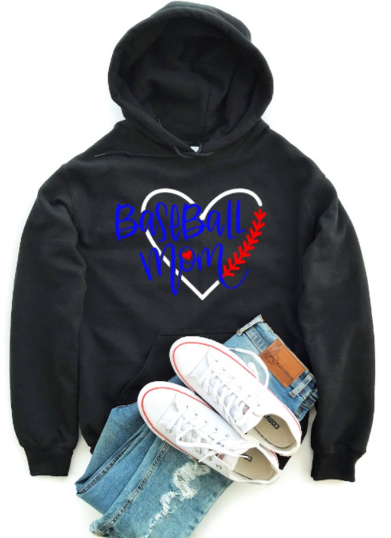 May include: Black hooded sweatshirt with a white heart and the text "Baseball Mom" in blue and red lettering. The heart has a red baseball stitch design.