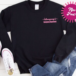 May include: Black sweatshirt with a pink graphic that reads "Emergency Emergency Department" with a heartbeat symbol.