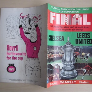 May include: A vintage program for the 1970 Football Association Challenge Cup Final between Chelsea and Leeds United. The program features a drawing of a player holding the trophy and the text "FINAL" in red letters.