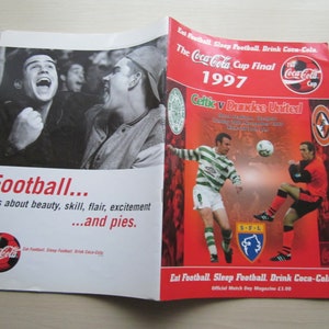 Könnte beinhalten: Ein rot-weißes Coca-Cola Cup Final Programm aus dem Jahr 1997 mit Celtic gegen Dundee United. Das Programm zeigt ein Foto von zwei Fußballspielern in Aktion. Der Text "Eat Football. Sleep Football. Drink Coca-Cola." ist unten auf dem Programm gedruckt.
