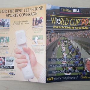 Puede incluir: Un folleto para la guía de recuerdos de la Copa Mundial 90 de William Hill Leisure. El folleto presenta una foto de jugadores de fútbol en un campo y un teléfono con el logotipo de William Hill. El folleto también incluye información sobre la opinión personal de Bobby Robson, gráficos de progreso, guías de apuestas, perfiles de equipo y cobertura televisiva.