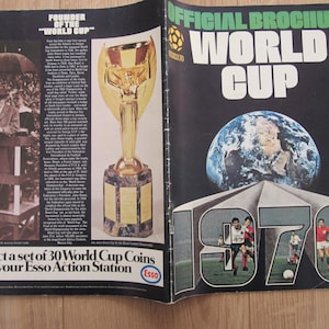 May include: A black and white brochure for the 1970 World Cup. The cover features a globe, a soccer field, and the text "Official Brochure World Cup 1970". The brochure is advertising a set of 30 World Cup coins available at Esso Action Stations.