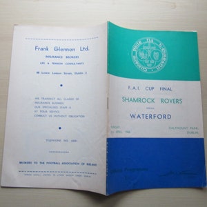 May include: A program for the F.A.I. Cup Final between Shamrock Rovers and Waterford on Sunday, April 2nd, 1968, at Dalymount Park in Dublin. The program is printed on white paper with blue and green accents. The front cover features the Shamrock Rovers crest and the text "F.A.I. Cup Final" and "Shamrock Rovers vs Waterford". The back cover features the text "Frank Glennon Ltd. Insurance Brokers Life & Pension Consultants 48 Lower Leeson Street, Dublin 2".