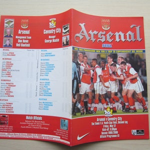 May include: A red and white programme for the Arsenal v Coventry City The Times F.A. Youth Cup Final, Second Leg on Friday, May 12. The programme features a photo of the Arsenal team celebrating a goal. The programme is from the 1998-2000 season.