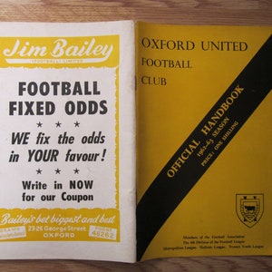 Può includere: Manuale vintage dell'Oxford United Football Club della stagione 1962-63. La copertina è gialla con strisce diagonali nere e testo. La pagina a sinistra presenta una pubblicità per Jim Bailey.