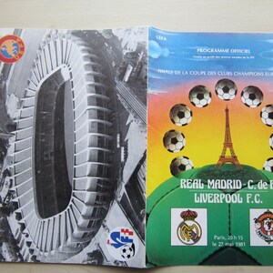 May include: A program for the 1981 European Cup Final between Real Madrid and Liverpool Football Club. The program features a photo of the Parc des Princes stadium in Paris, France, where the match was played. The program also includes the logos of both teams and the date of the match.