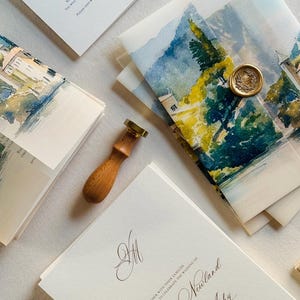 Peut inclure: Ensemble de faire-part de mariage avec des paysages à l'aquarelle sur les enveloppes. L'ensemble comprend des cartons d'invitation, des cartons de réponse et des enveloppes scellées avec un cachet de cire doré. Le texte de l'invitation comprend les noms de Michelle & Victor Ashy.
