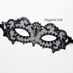 Puede incluir: M&aacute;scara de encaje negro para mascarada con pedrer&iacute;a y lazos de cinta negra. La m&aacute;scara tiene un delicado dise&ntilde;o floral.