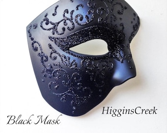 May include: A black mask with glitter detailing and a decorative swirl pattern. The mask features an eye opening and is made of a matte black material. The text "Black Mask", "Black Glitter", and "Shown" are visible.