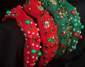 Op de afbeelding: Vier kerst haarbanden in rood en groen, versierd met feestelijke versieringen. Elke haarband heeft een geknoopt ontwerp en is versierd met kralen, edelstenen en feestelijke bedels. De haarbanden worden gepresenteerd tegen een donkere achtergrond.