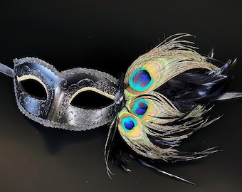 Puede incluir: Una máscara de carnaval negra con un acento de pluma de pavo real. La máscara tiene un borde dorado y la pluma es verde, azul y dorada.