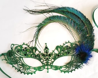 May include: A green lace masquerade mask with a peacock feather accent. The mask has a delicate design and is adorned with rhinestones.