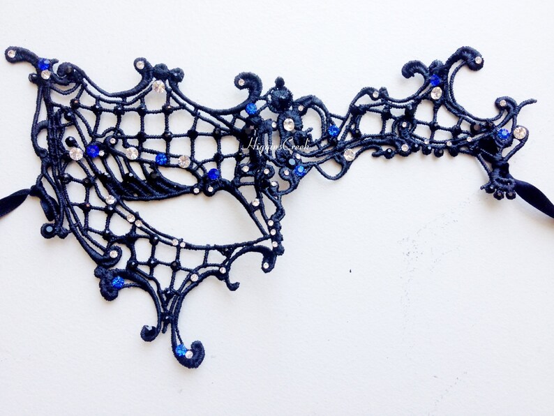May include: Black lace masquerade mask with blue and clear rhinestones. The mask has a delicate, intricate design and is perfect for a masquerade ball or costume party.