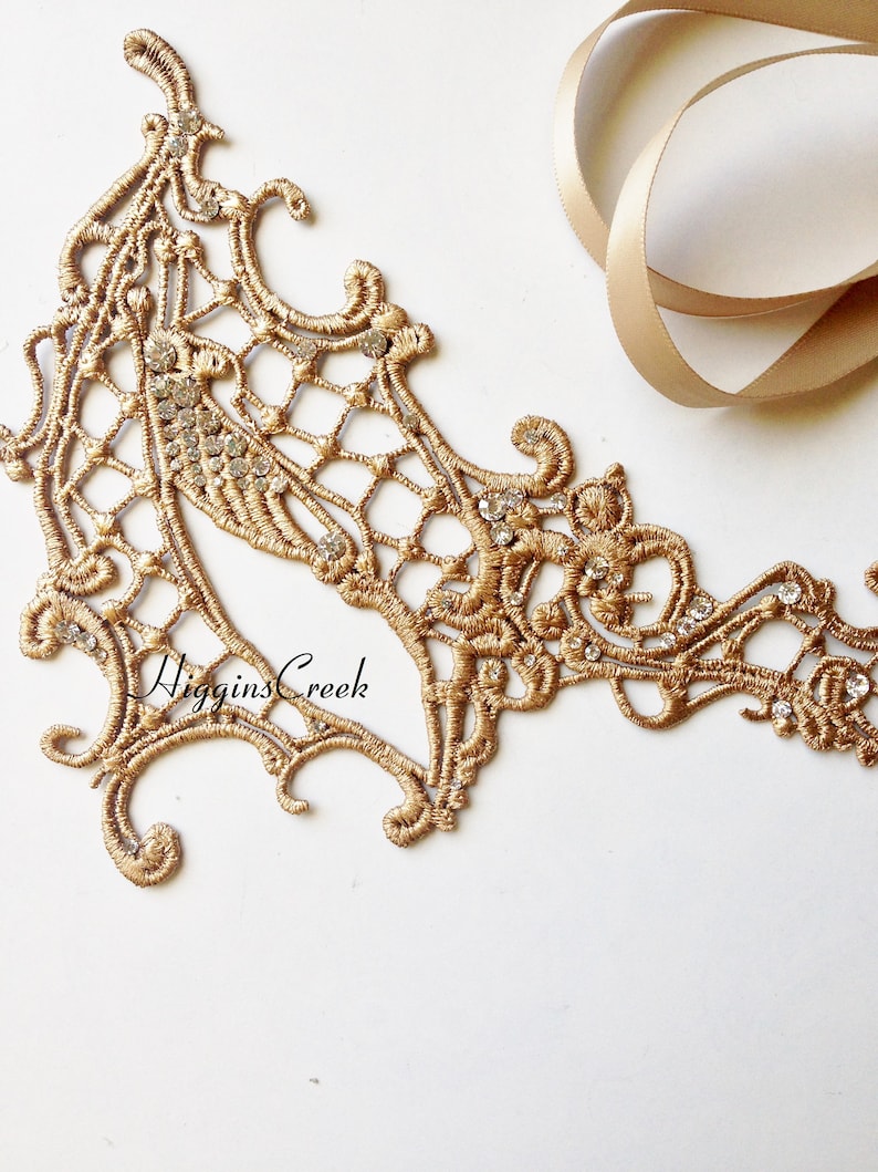 May include: Gold lace trim with a delicate floral design and clear rhinestones. The trim is perfect for adding a touch of elegance to any project.