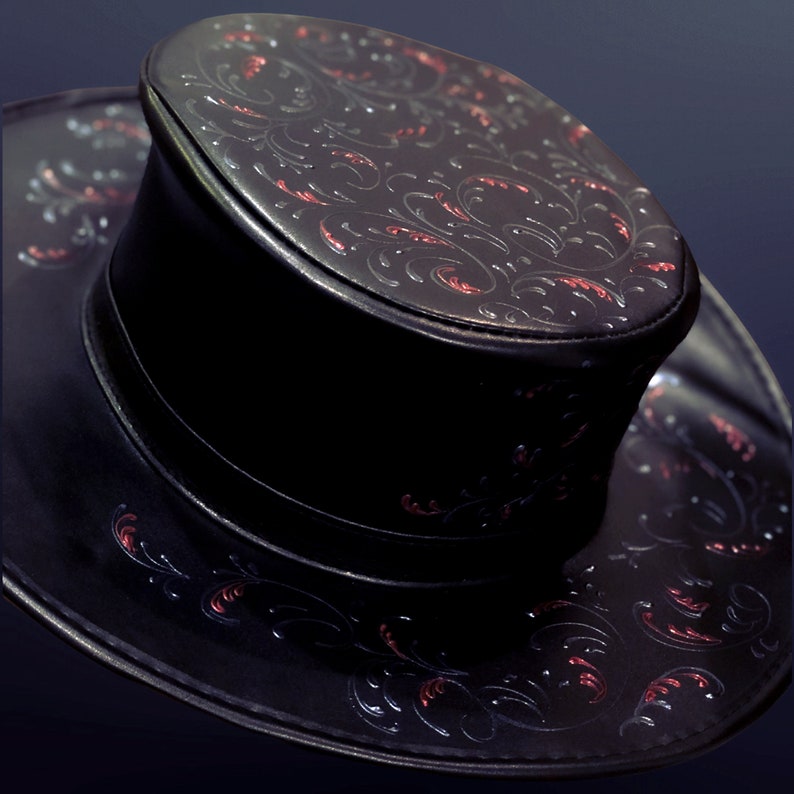 May include: A black leather hat with a wide brim and a tall crown. The hat is decorated with a red and silver floral pattern.
