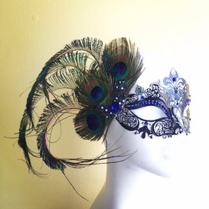 May include: A black masquerade mask with blue and silver accents and a peacock feather embellishment.