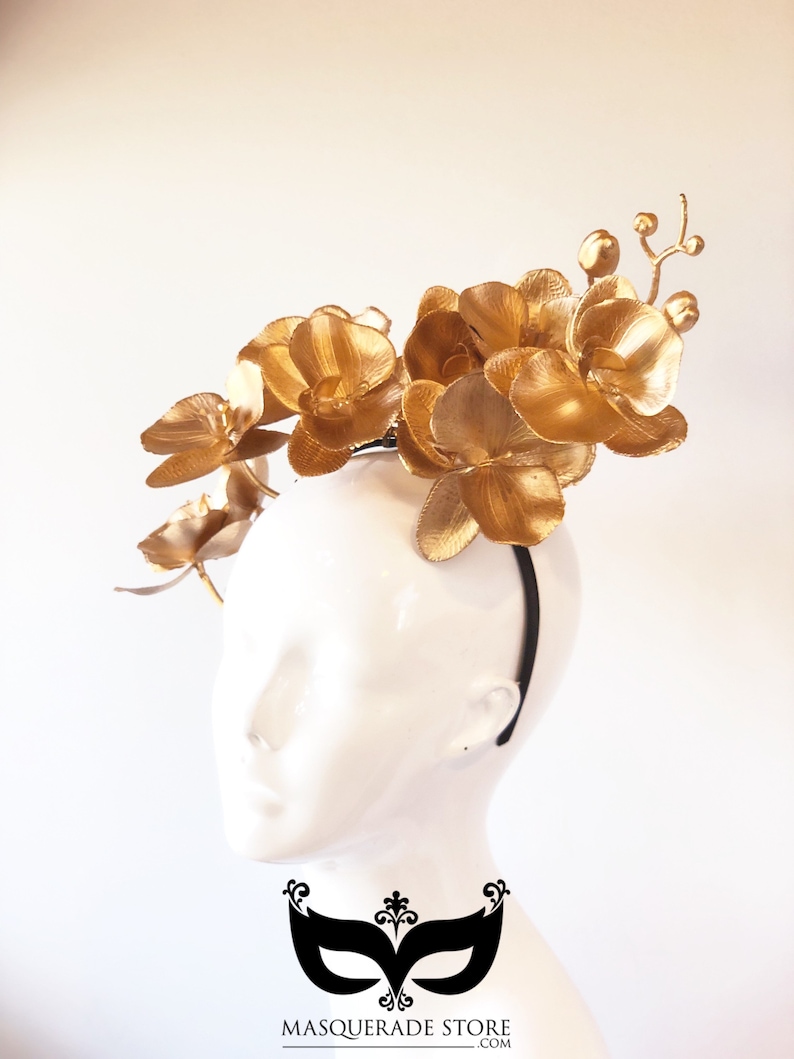 May include: Gold orchid flower headband with a black elastic band. The headband is decorated with multiple gold orchid flowers.