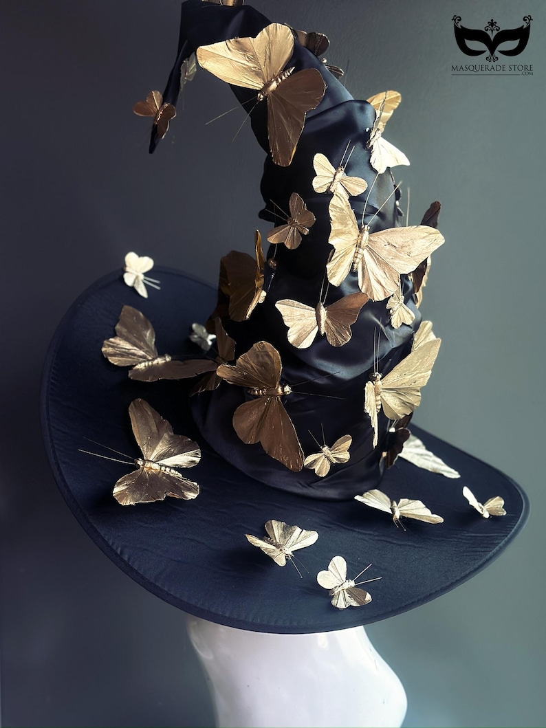 May include: A black witch hat adorned with numerous gold-colored butterfly decorations. The hat has a wide brim and a tall, pointed crown. The butterflies are of varying sizes and are attached to the hat.