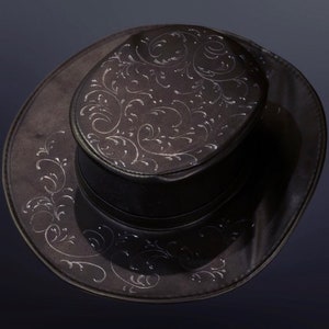 Puede incluir: Un sombrero de copa negro con un dise&ntilde;o floral plateado. El sombrero tiene un ala ancha y una copa alta.