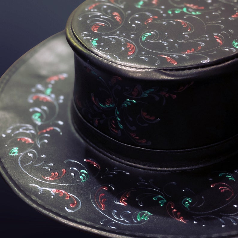 May include: A black leather hat with a wide brim and a crown decorated with a floral pattern in red, green, and silver.