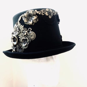 May include: A black top hat with a wide brim and a decorative design of silver flowers, chains, and gears.