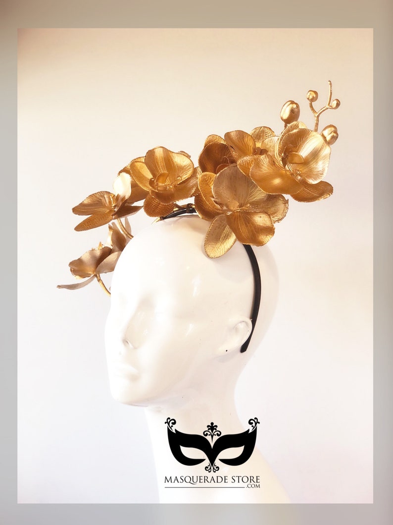 May include: Gold orchid headband with a black elastic band. The headband is decorated with several gold orchid flowers.