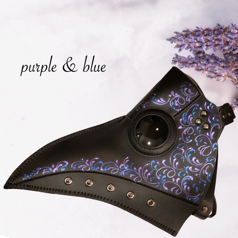 May include: A black leather plague doctor mask with a round eye piece and a long beak. The mask is decorated with a swirling pattern in purple and blue.